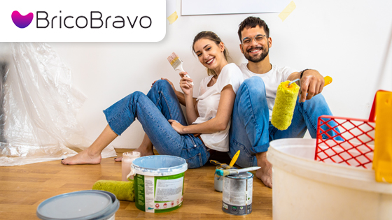 Due persone sedute sul pavimento con rulli e barattoli di vernice durante lavori domestici Bricobravo