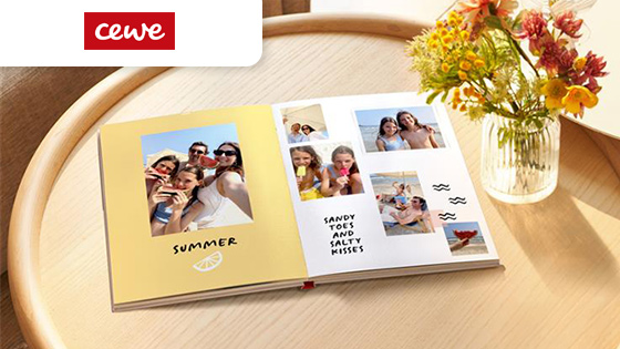 Cewe fotolibro su tavolino illuminato dal sole per raccogliere le foto con amici e familiari dell'estate