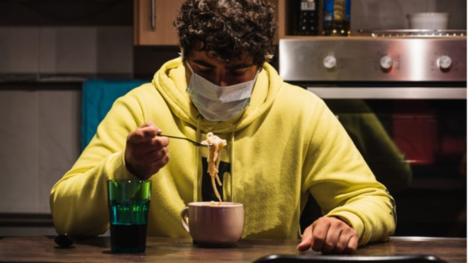 ragazzo cn mascherina che mangia da una tazza