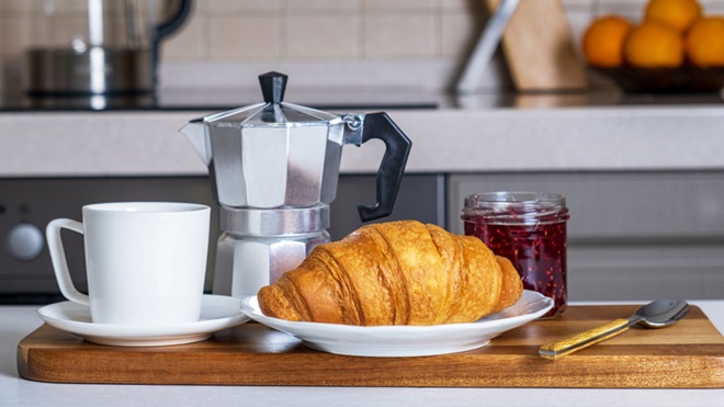caffettiera, tazza, brioche e marmellata sul tavolo della cucina