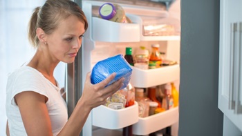 Donna guarda cibo dal frigorifero