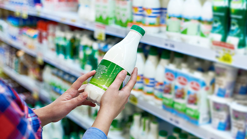 mani impugnano una bottiglia di latte