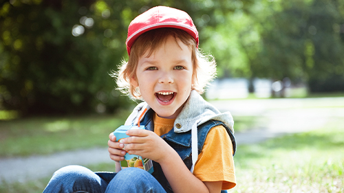 bimbo che sorride con in mano un succo di frutta