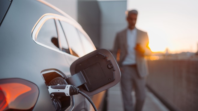 Auto elettrica in ricarica al tramonto