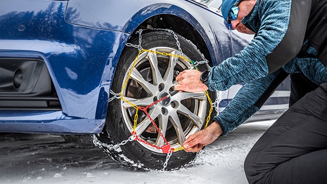 Uomo monta catene da neve sullo pneumatico dell'automobile