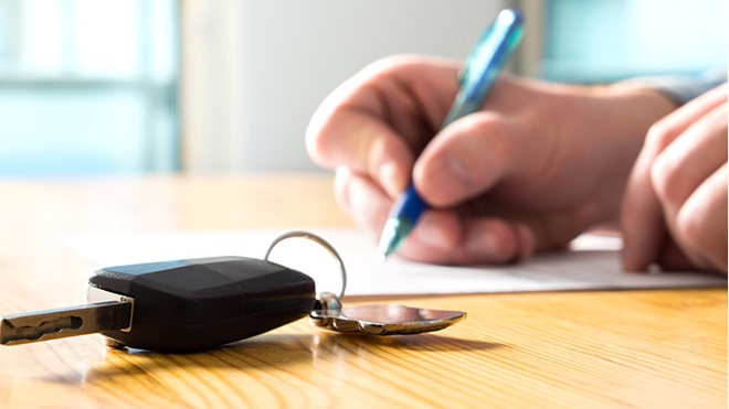 primo piano chiave auto e mano che firma