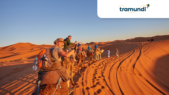 Gente nel deserti sui cammelli e logo Tramundi