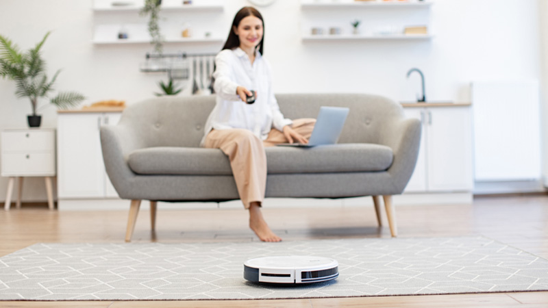 donna su divano telecomanda robot aspirapolvere