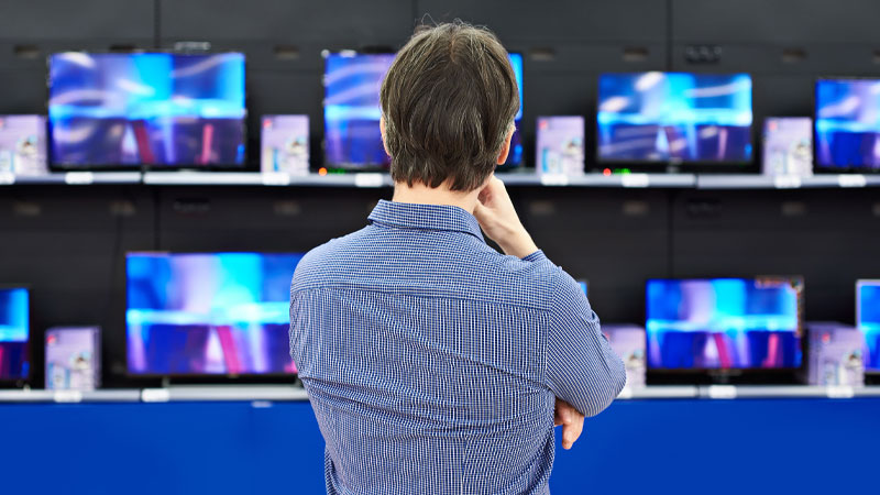 uomo di spalle guarda schermi tv