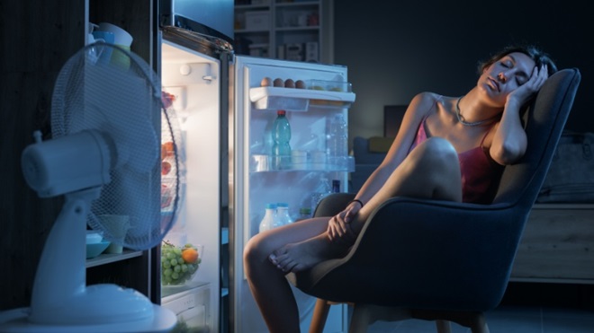 Ragazza davanti a frigorifero con ventilatore acceso