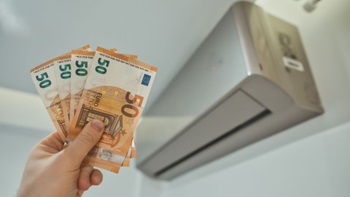 Split del climatizzatore e mano con banconote da 50 euro