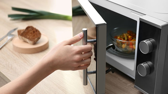 mano che apre forno a microonde