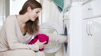 ragazza mette il bucato in lavatrice