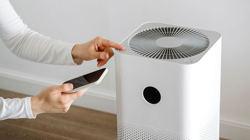 mani con smartphone e purificatore d'aria