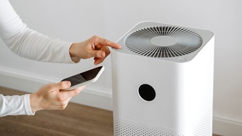 mani con smartphone e purificatore d'aria