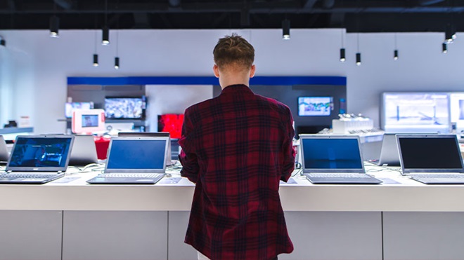 uomo che guarda una serie di PC portatili