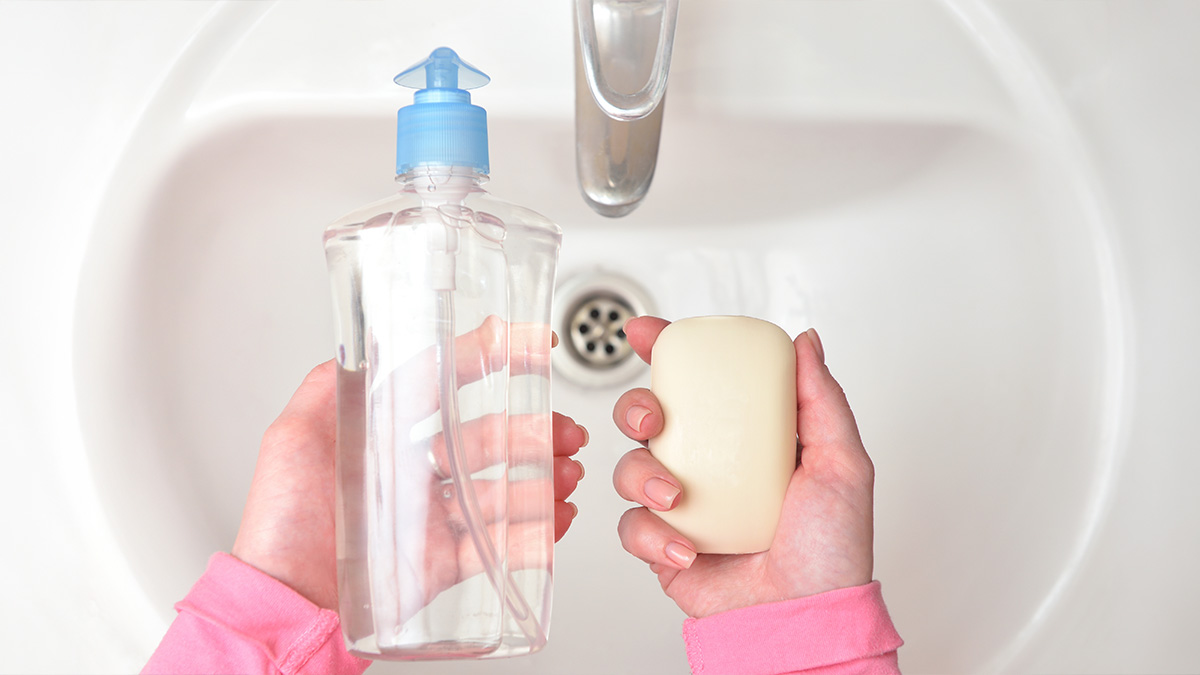 mani stringono barattolo e sapone sopra un lavello
