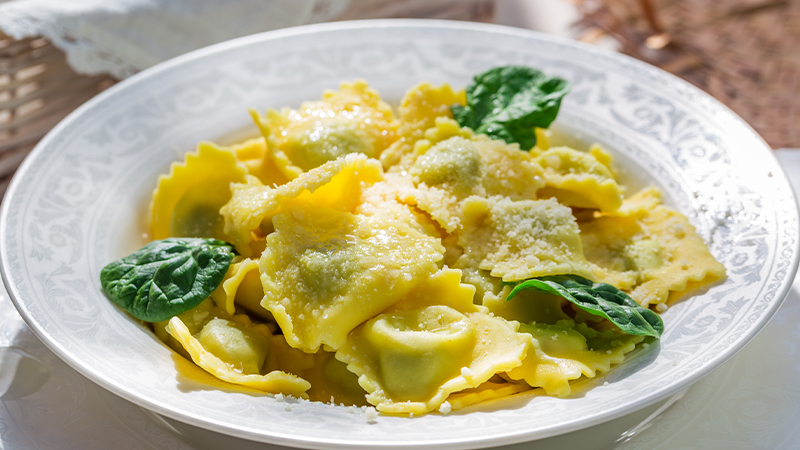 piatto di ravioli con formaggio e foglie di basilico