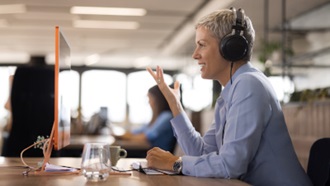 donna con cuffie parla davanti a pc