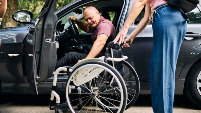 disabile in carrozzina vicino all'auto