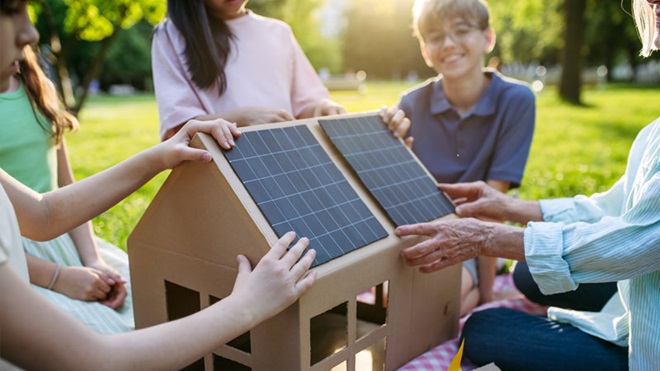 ragazzi e modello di casa con tetto a pannelli fotovoltaici