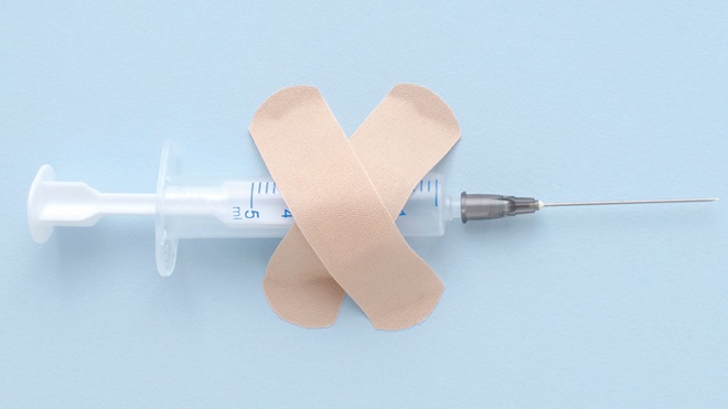 siringa con sopra una x fatta di cerotti