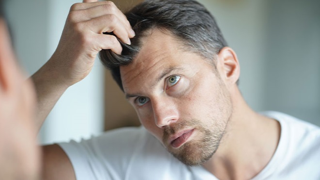uono che si guarda l'attaccatura dei capelli