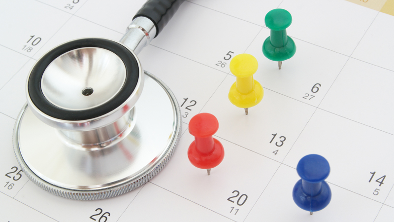 sfigmomanometro e puntine colorate appoggiate su un calendario