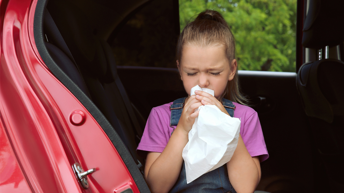 Bambina seduta in auto che soffia in un sacchetto di carta