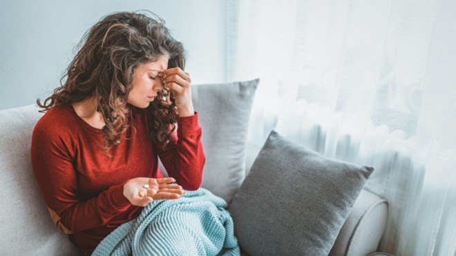 Ragazza con mal di testa e pastiglia in una mano