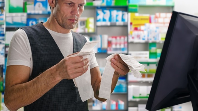 Uomo in farmacia con in mano degli scontrini fiscali