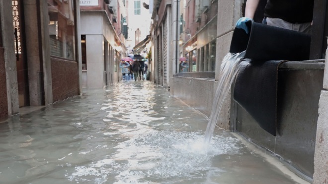 Strada allagata con secchio alla finestra