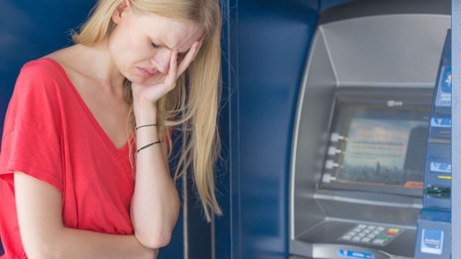 Donna triste accanto allo sportello bancomat