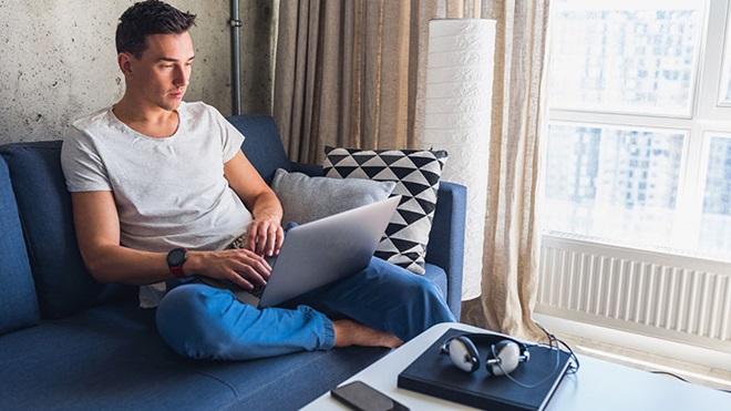 ragazzo seduto sul divano con PC sulle gambe