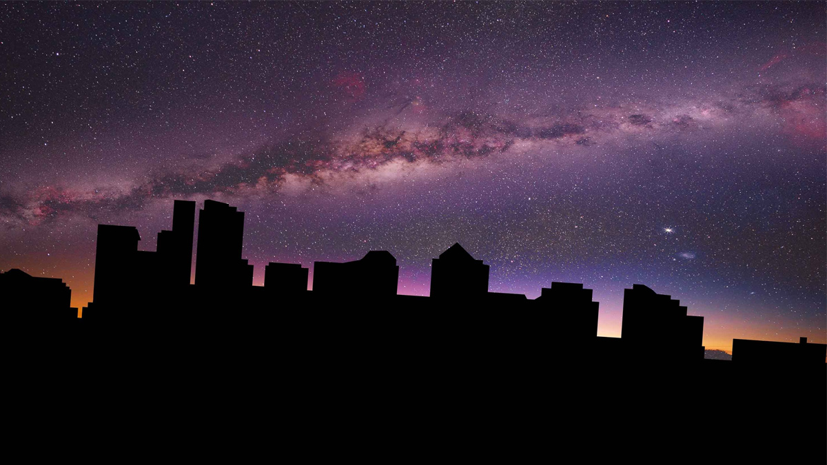 Skyline cittadino in silhouette al buio durante un blackout, sotto un cielo notturno stellato con la Via Lattea visibile