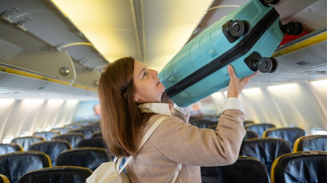 donna carica bagaglio a mano in cappelliera aereo