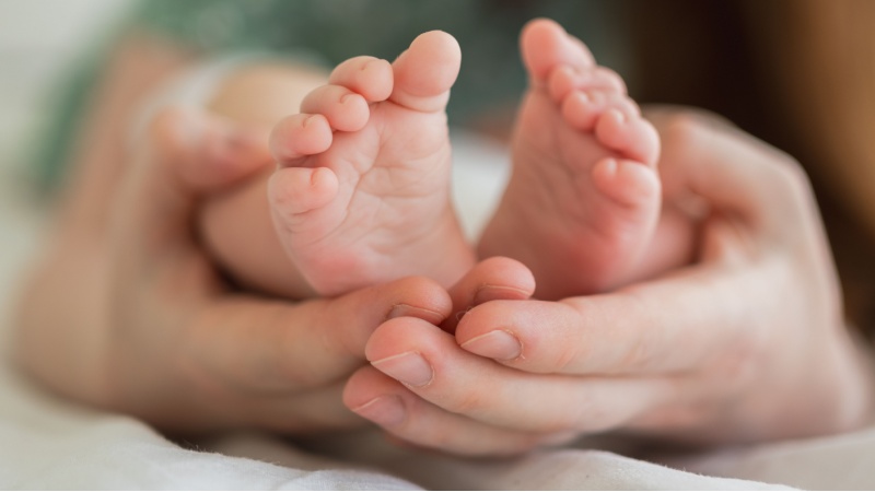 Piedini di un neonato e mani di un adulto