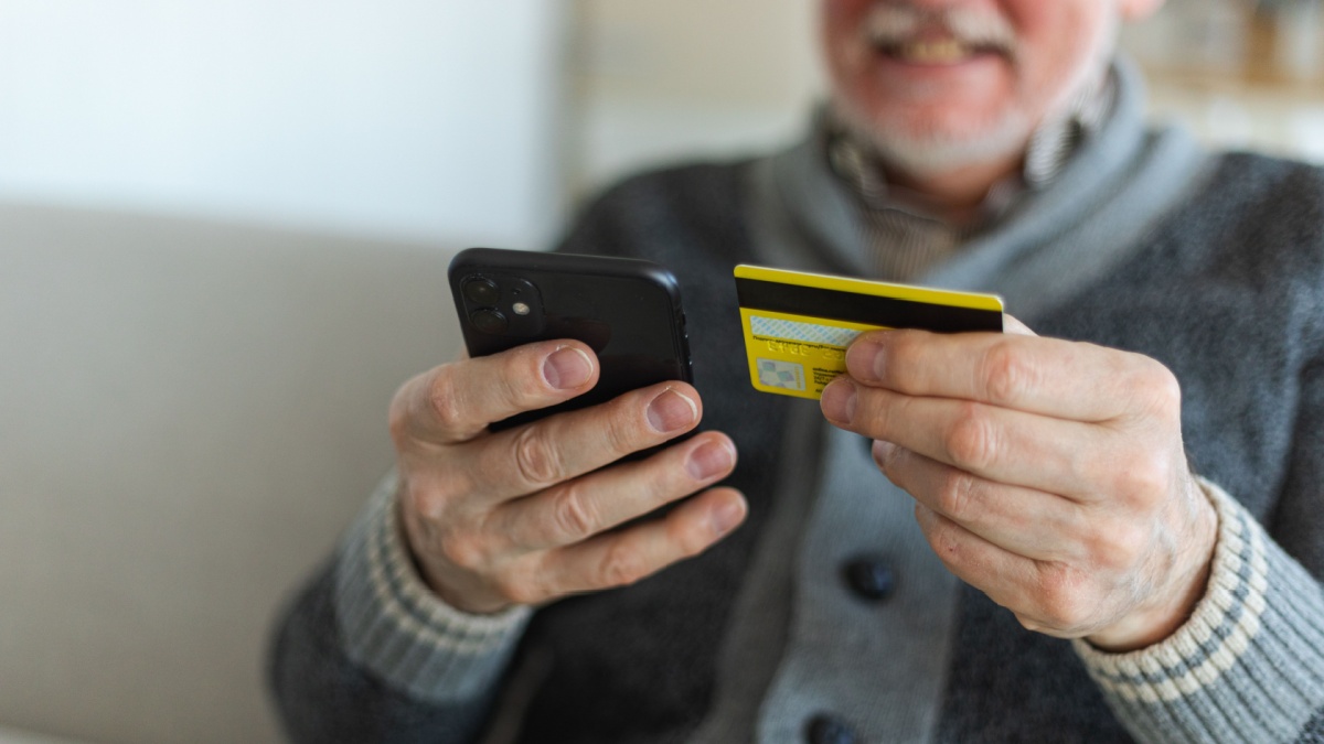 Anziano con carta di credito e smartphone