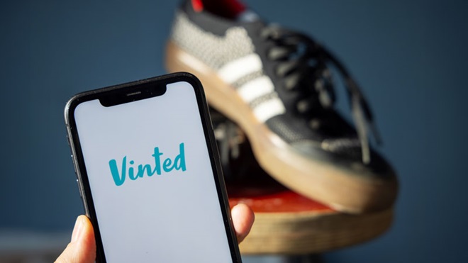 smartphone con logo Vinted e scarpe