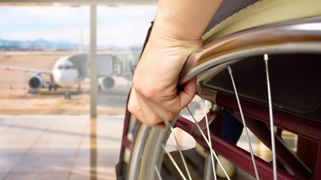 primo piano di mano su ruota sedia a rotelle in aeroporto