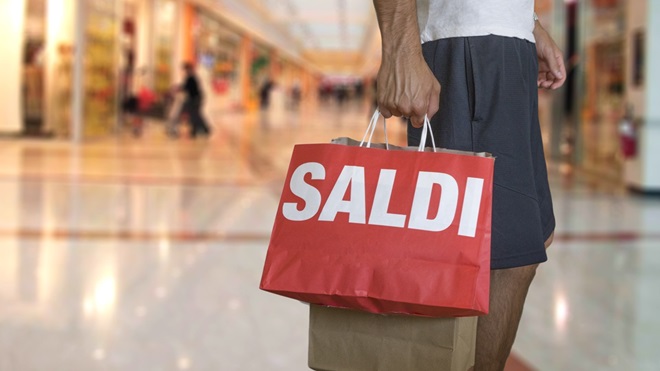 Ragazzo con sacchetti e scritta saldi