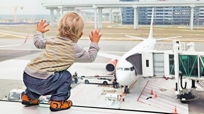 Bimbo in aeroporto guarda l'aereo fuori dal vetro