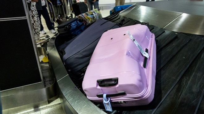 Valigia danneggiata e ammaccata che circola sul nastro trasportatore del terminal dell'aeroporto a causa di una manipolazione brusca