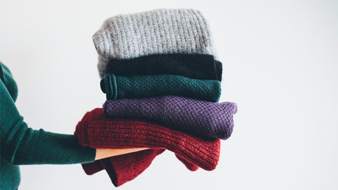 mano che regge maglioni piegati