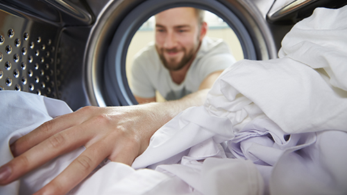 uomo che guarda panni nella lavatrice