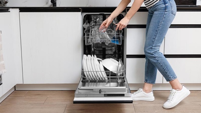 LAVASTOVIGLIE COMPATTA CON DONNA CHE LA CARICA IN CUCINA