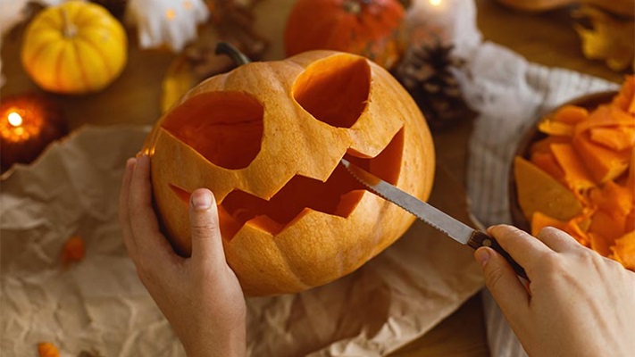 Persona che intaglia una zucca di Halloween