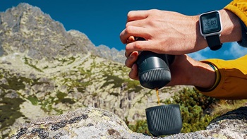 primo piano mano con macchina caffè portatile in montagna